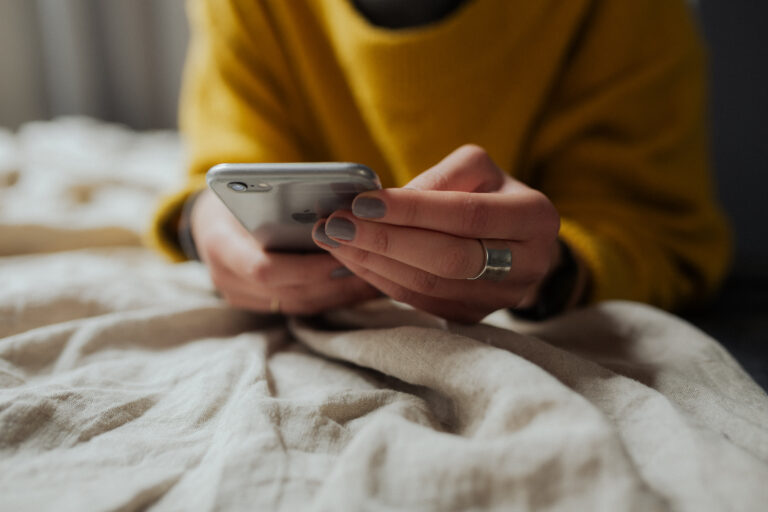 mulher no telemóvel à procura de plataformas para trabalhar como assistente virtual em portugal